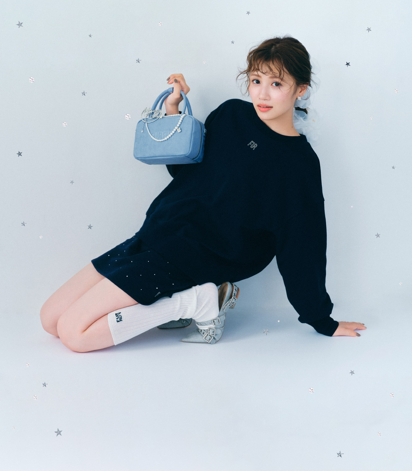 ネイビーのクリスタルロゴスウェットセットアップを着てサックスブルーのバリエーションスクエアボストンバッグを持った女性のメインビジュアル