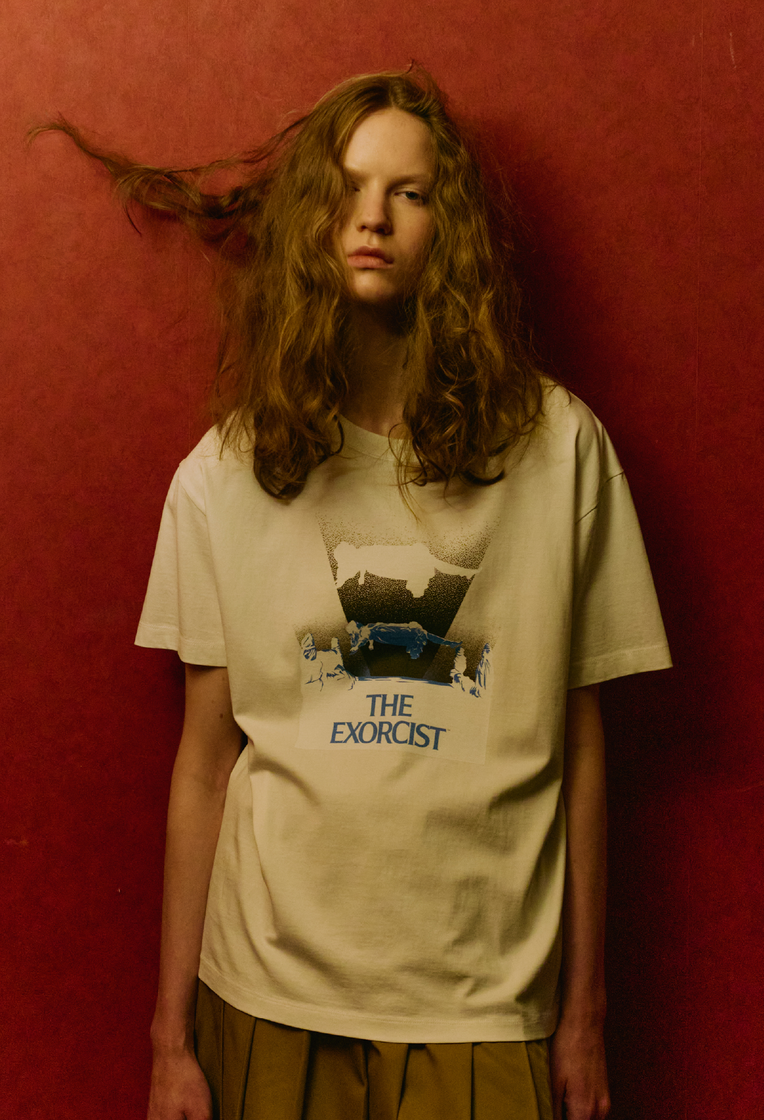 【THE EXORCIST】 グラフィックＴシャツ・レイヤードプリーツスカート・【THE EXORCIST】ブックバッグ・マルチウェイベルトバッグ・レースタイツを着用した女性